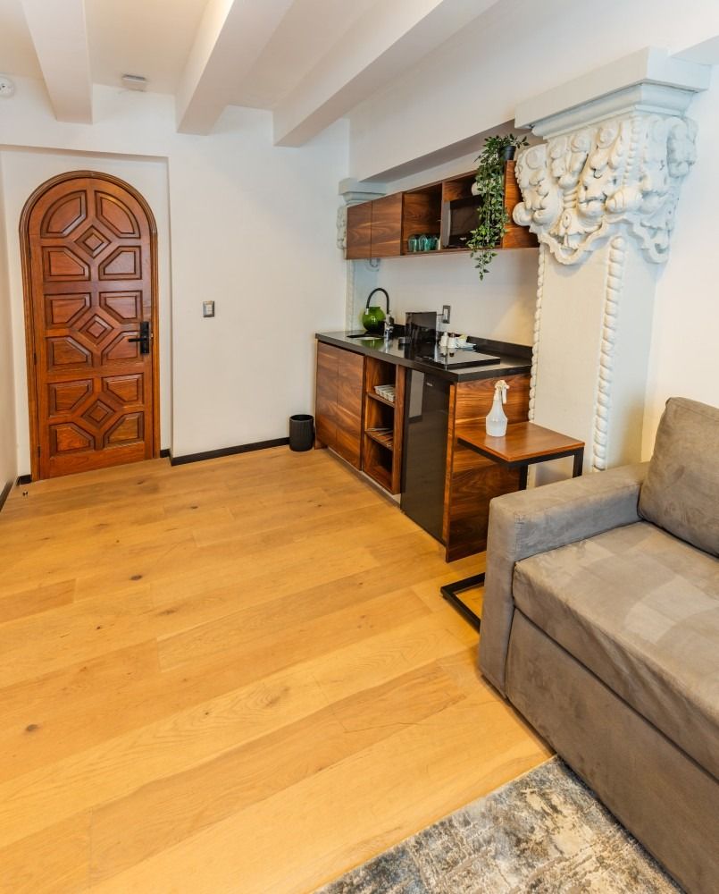 Una sala de estar con un sofá y una cocina al fondo.