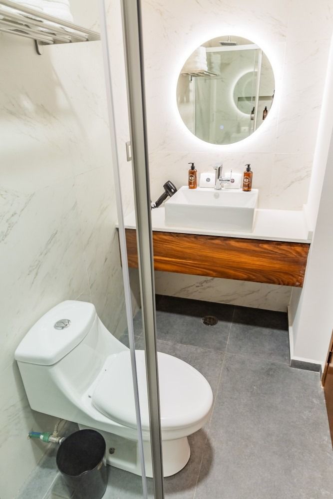 A bathroom with a toilet , sink and mirror.