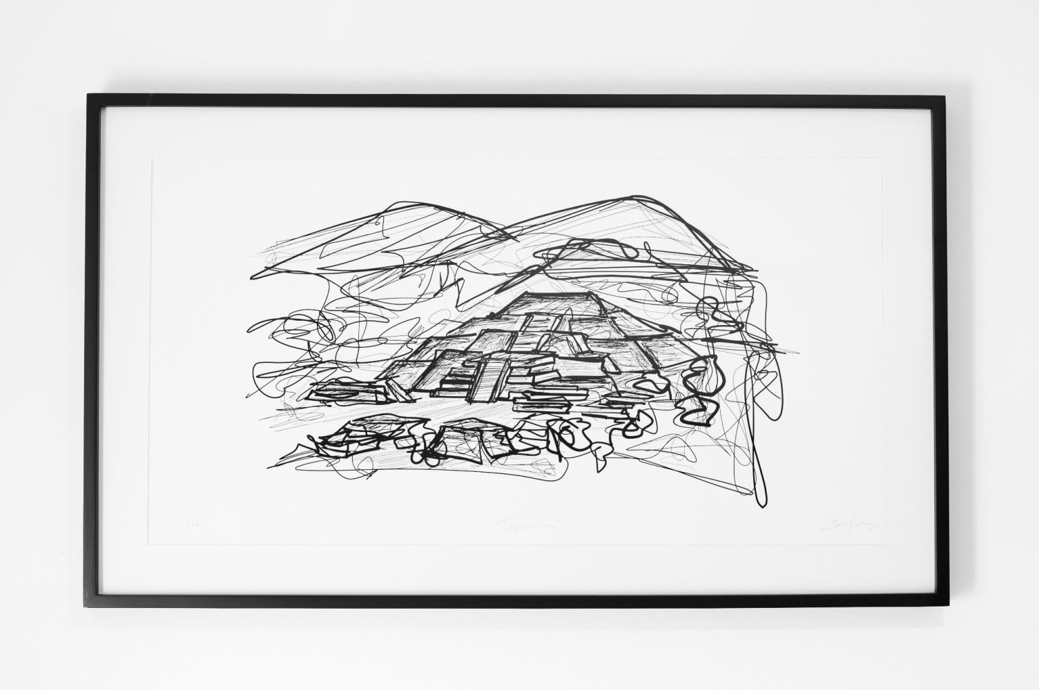 Un dibujo en blanco y negro de una montaña en un marco sobre una pared blanca.