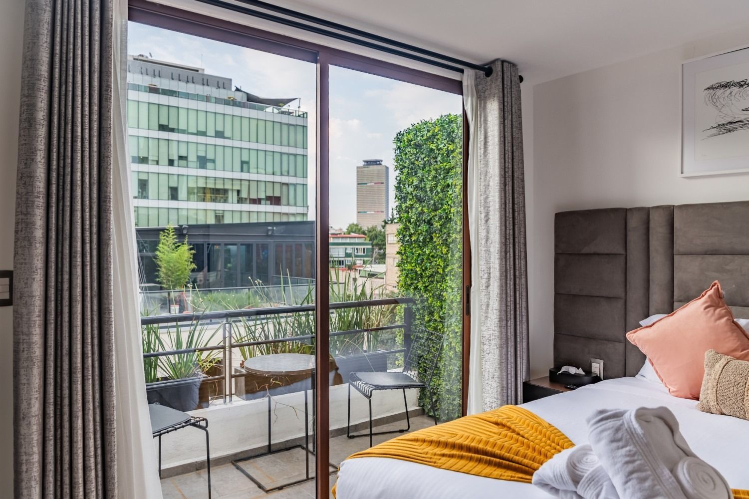 Una habitación de hotel con cama, balcón y puertas corredizas de vidrio.