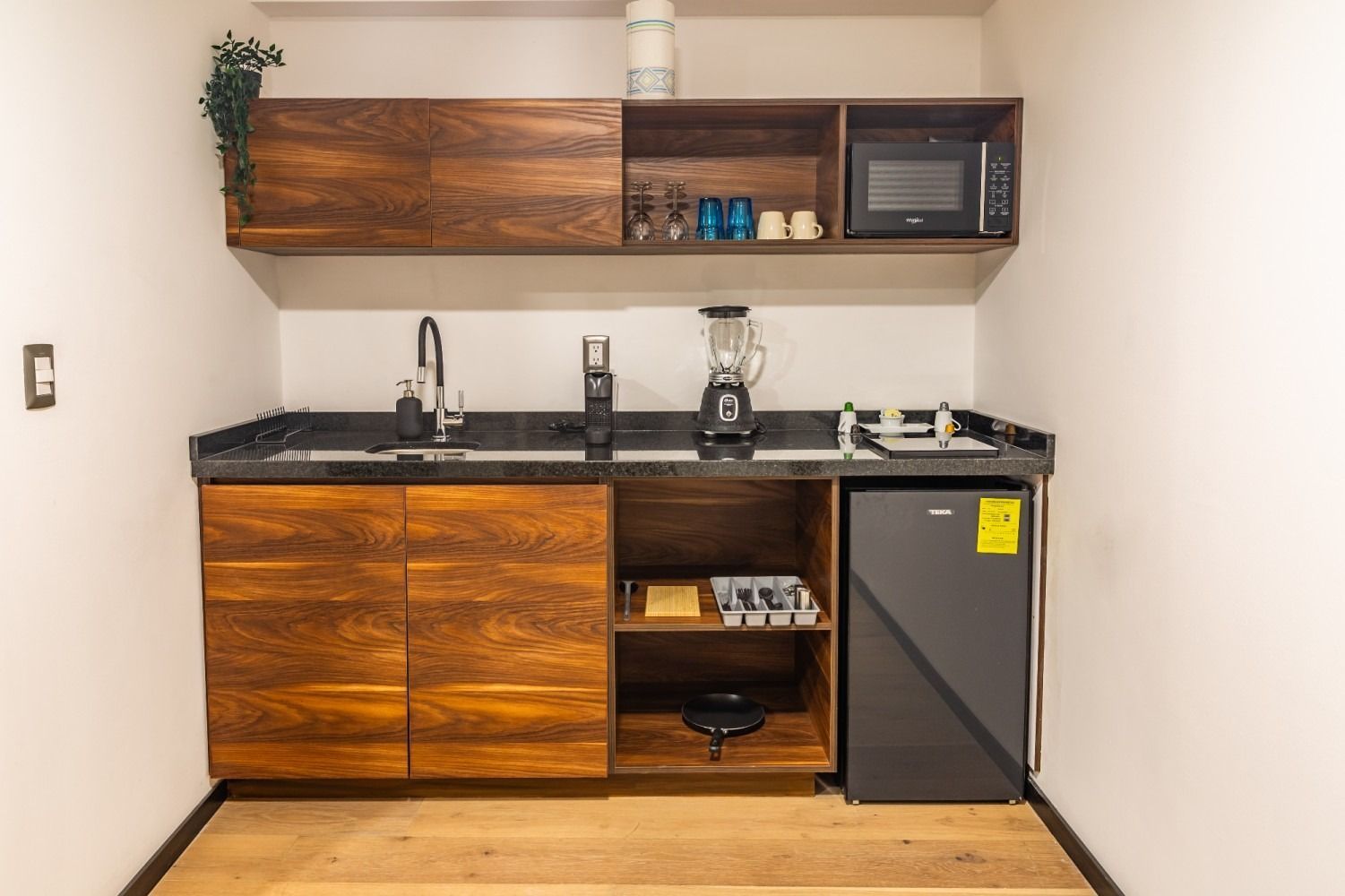 Una cocina con fregadero, licuadora, microondas y refrigerador.