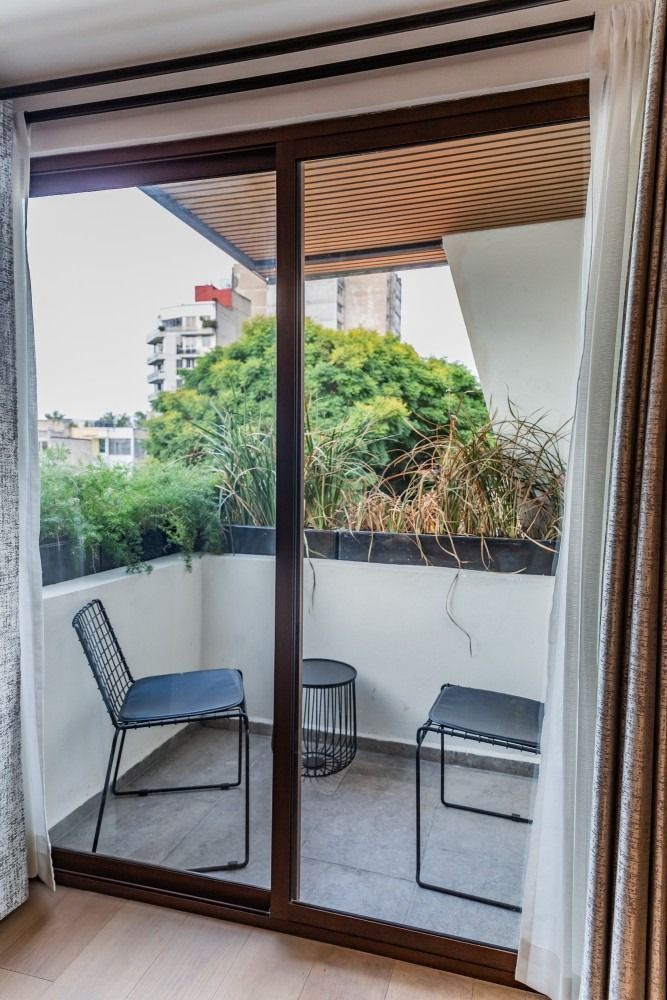 Un balcón con dos sillas y una mesa en una habitación con una puerta corrediza de vidrio.