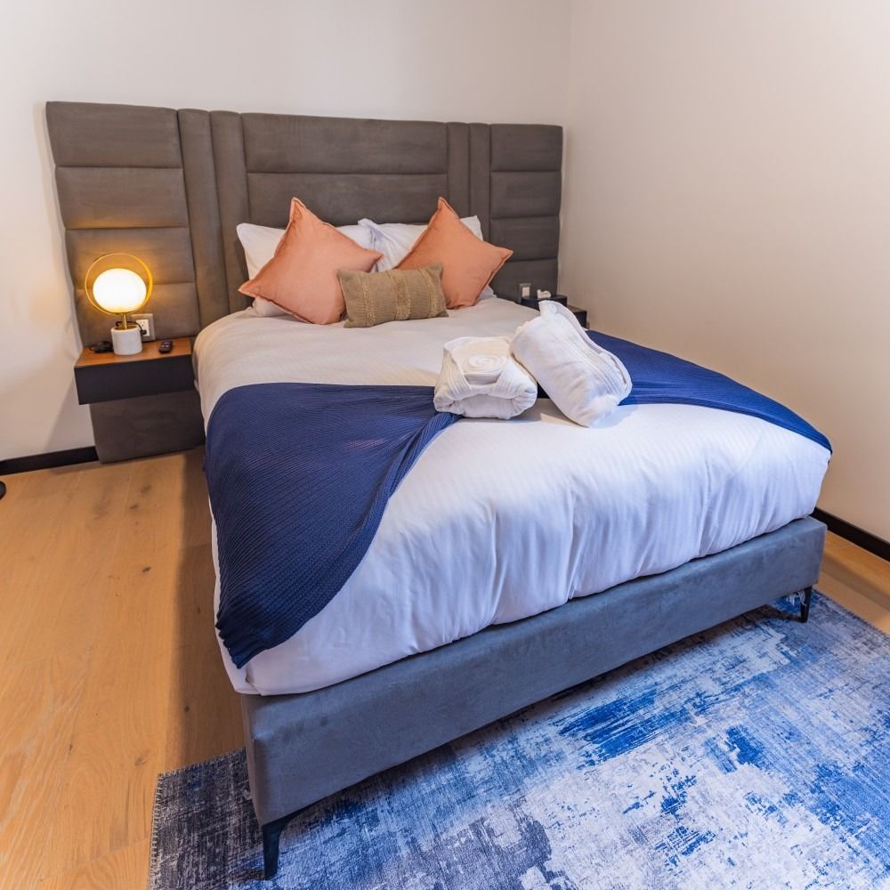 Un dormitorio con una cama grande y una alfombra azul.