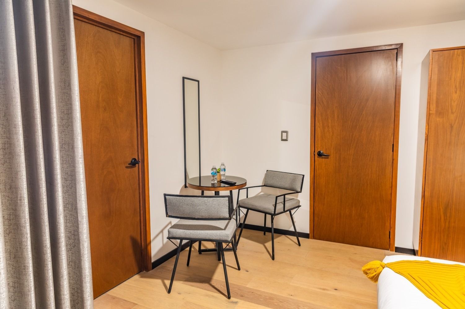 Una habitación de hotel con una mesa y sillas y un espejo.