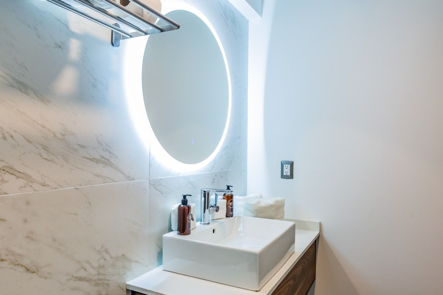 Un baño con lavabo, espejo y toallero.