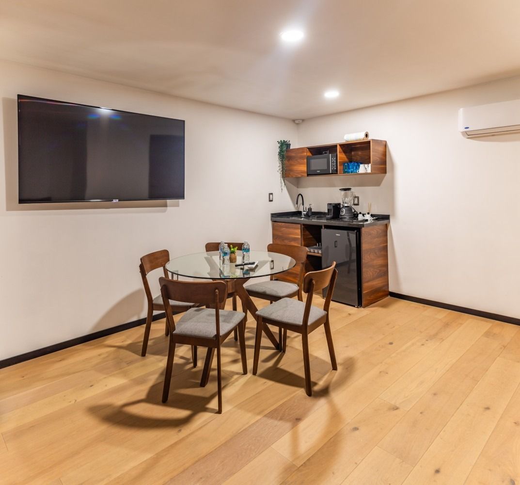 Una habitación con una mesa y sillas y un televisor de pantalla plana en la pared.