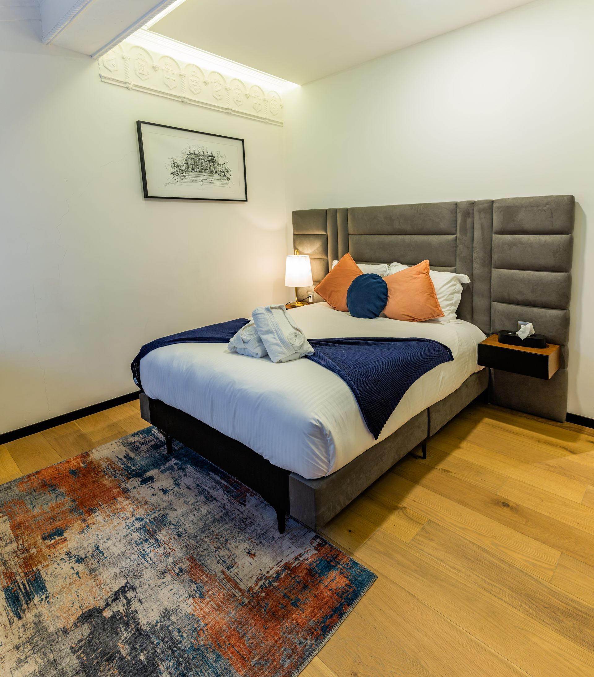 Un dormitorio con una cama y una alfombra en el suelo.