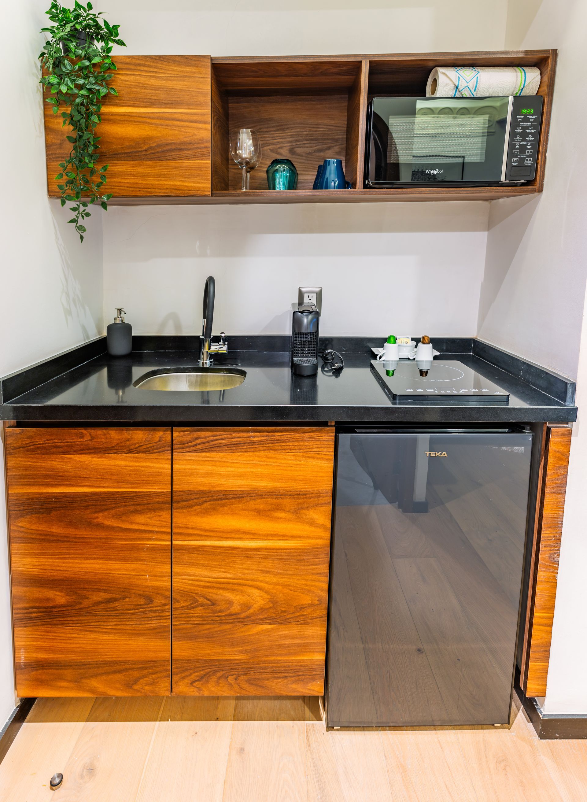 Una pequeña cocina con gabinetes de madera, un fregadero, un microondas y un refrigerador.