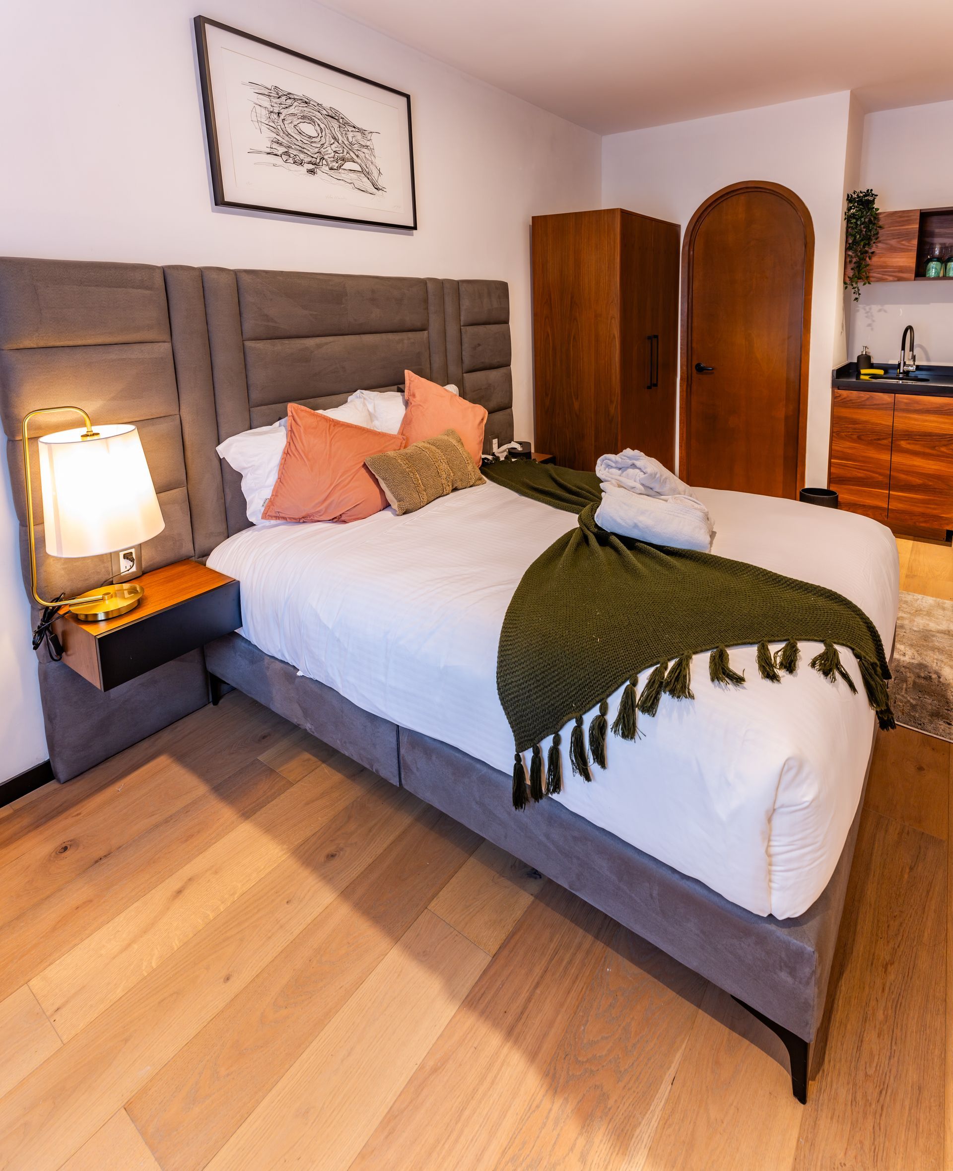 Un dormitorio con una cama grande y una lámpara en la mesita de noche.