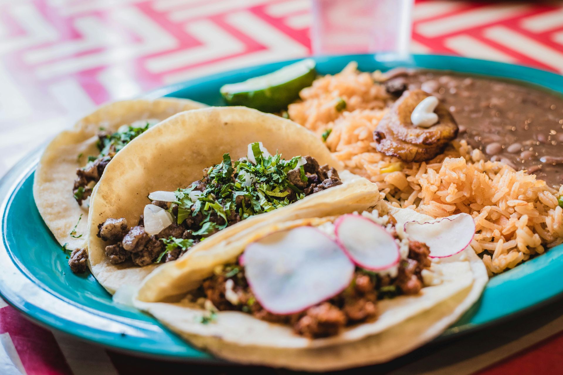 Un plato de tacos, arroz y frijoles en una mesa.