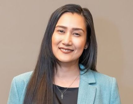 Smiling woman in a light blue blazer against a neutral background