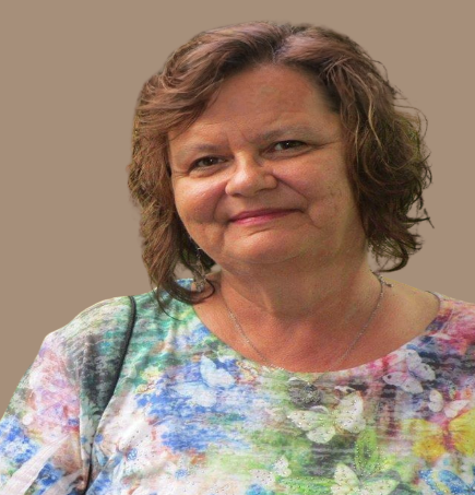 Woman smiling in a pastel floral blouse against a plain tan background