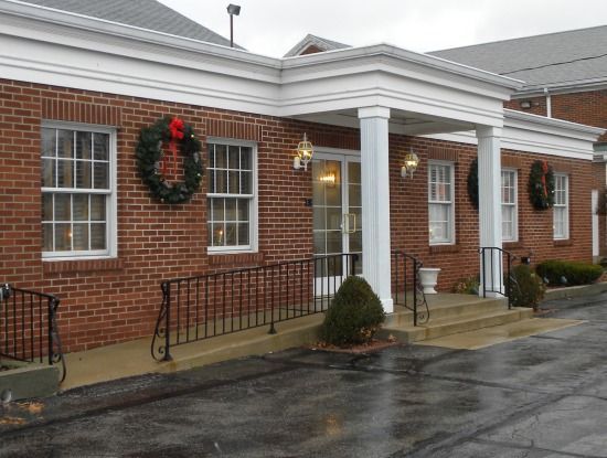 A brick building with a white porch and a wreath on the windows