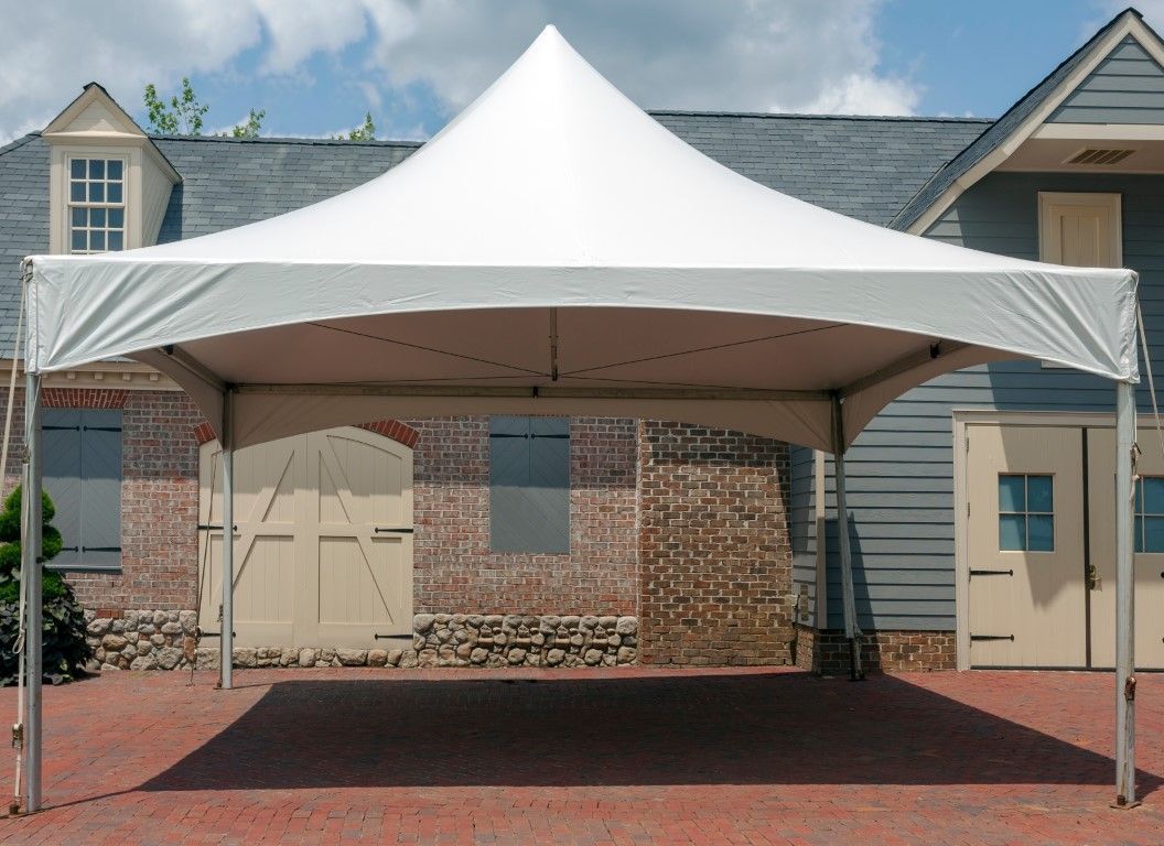 White canopy tent over a brick driveway in front of a house