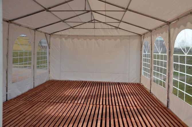 Empty white event tent with a wooden floor and arched side windows