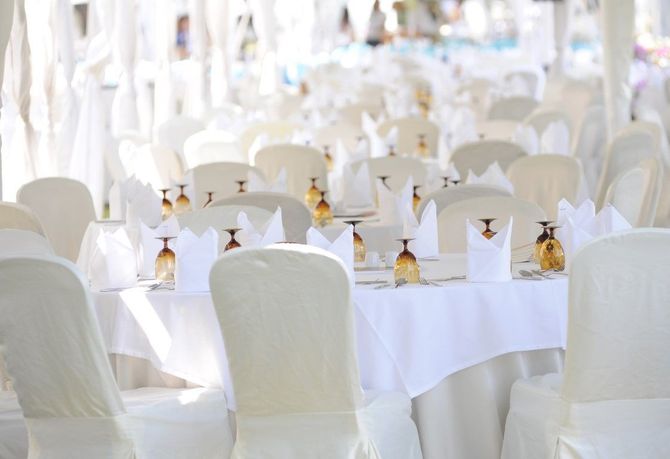 Rows of white-covered banquet chairs and tables set for an elegant outdoor event