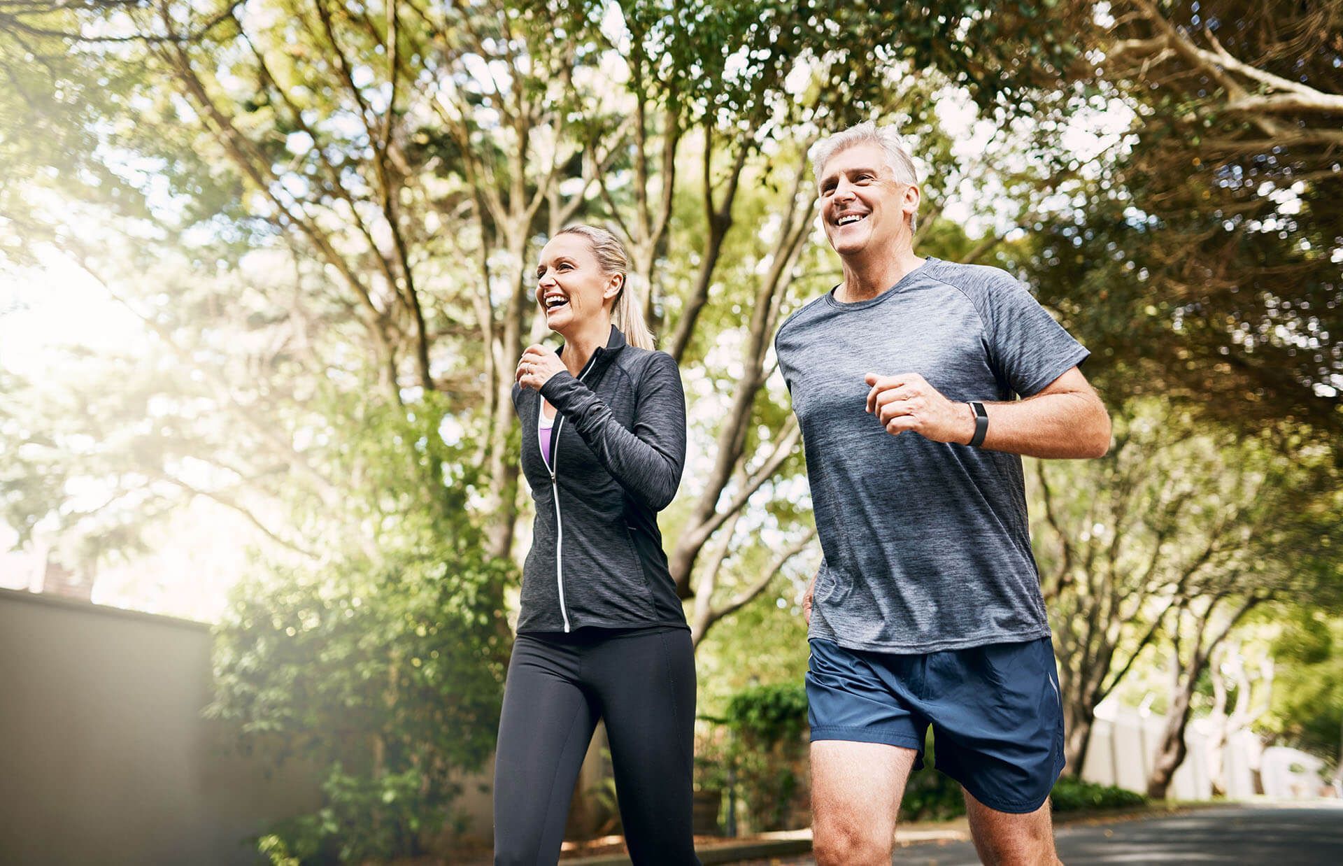 A 55+ man and a woman are jogging on a street.