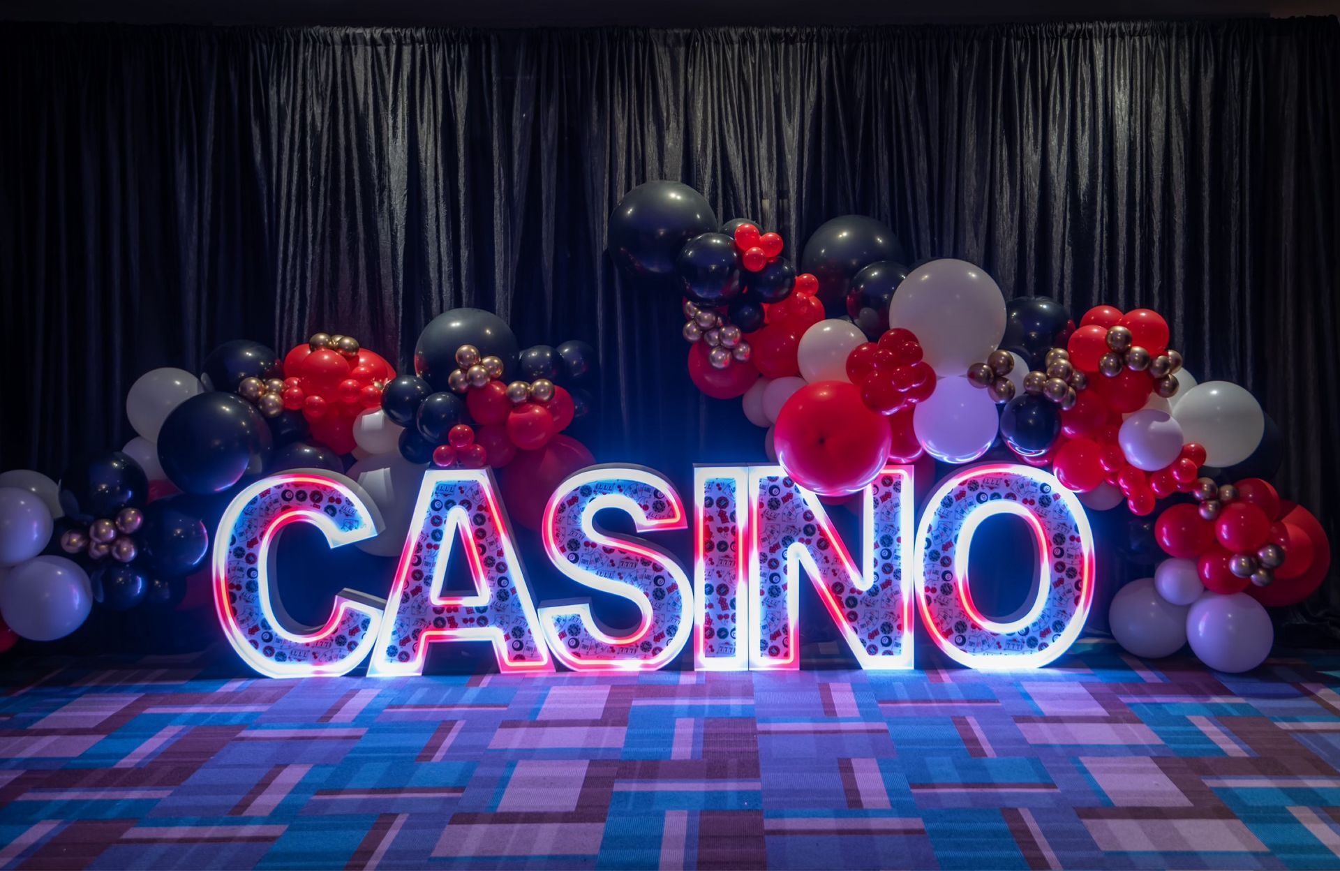 A large neon sign that says casino is surrounded by balloons.