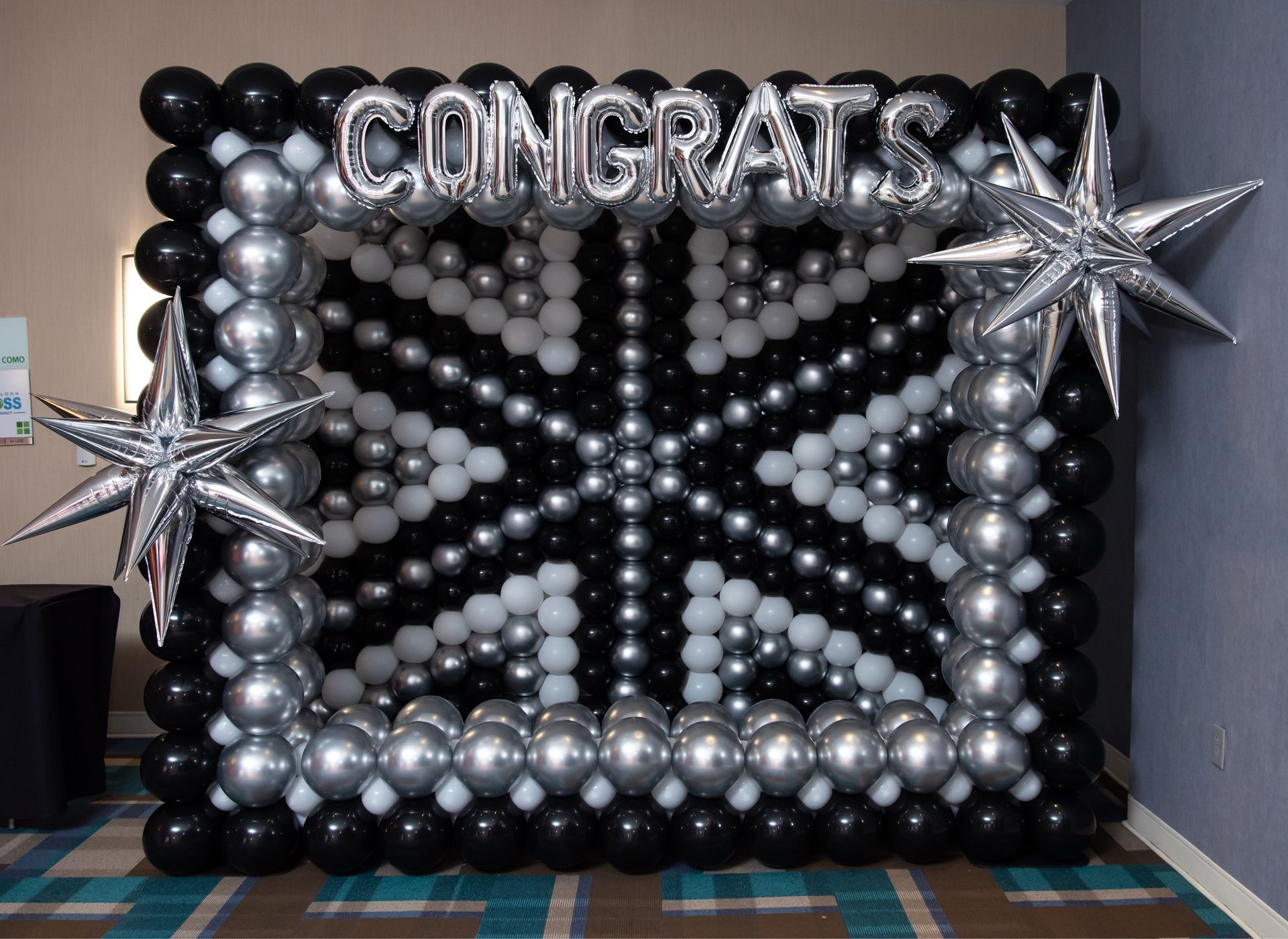 A black and white balloon wall with the words `` congratulations '' written on it.