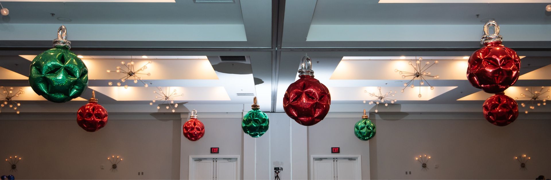 Red and green christmas ornaments are hanging from the ceiling of a room.