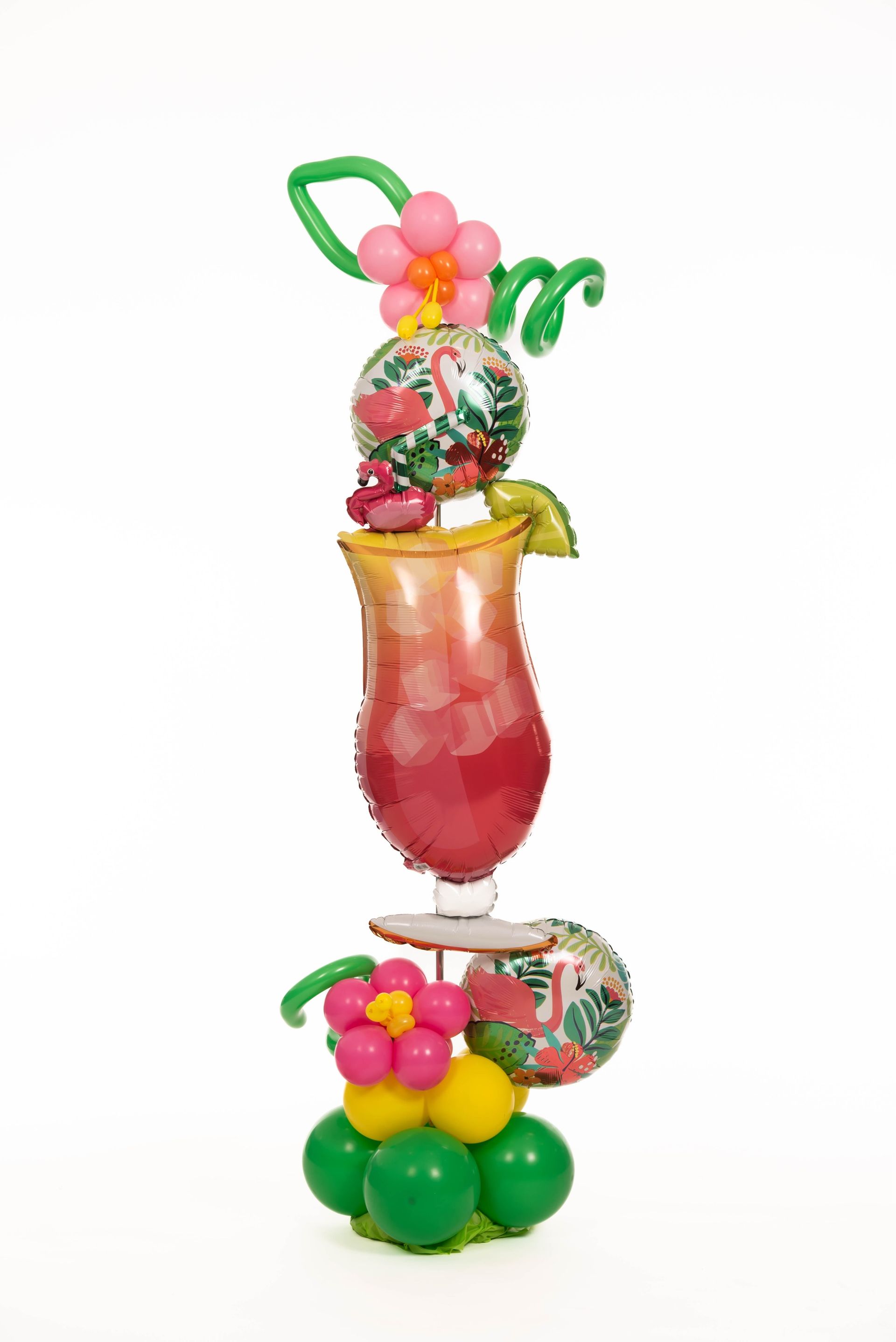 A tall glass filled with a pink drink is decorated with balloons.