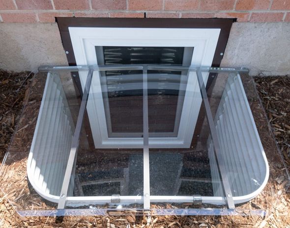 Egress window well cover against a stone wall