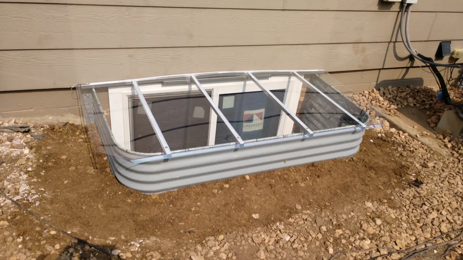 Egress window well cover against a stone wall