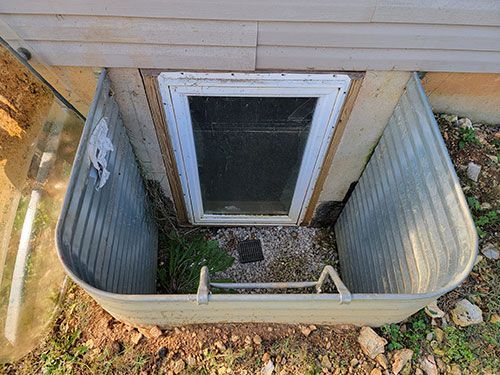 Egress window well cover against a stone wall