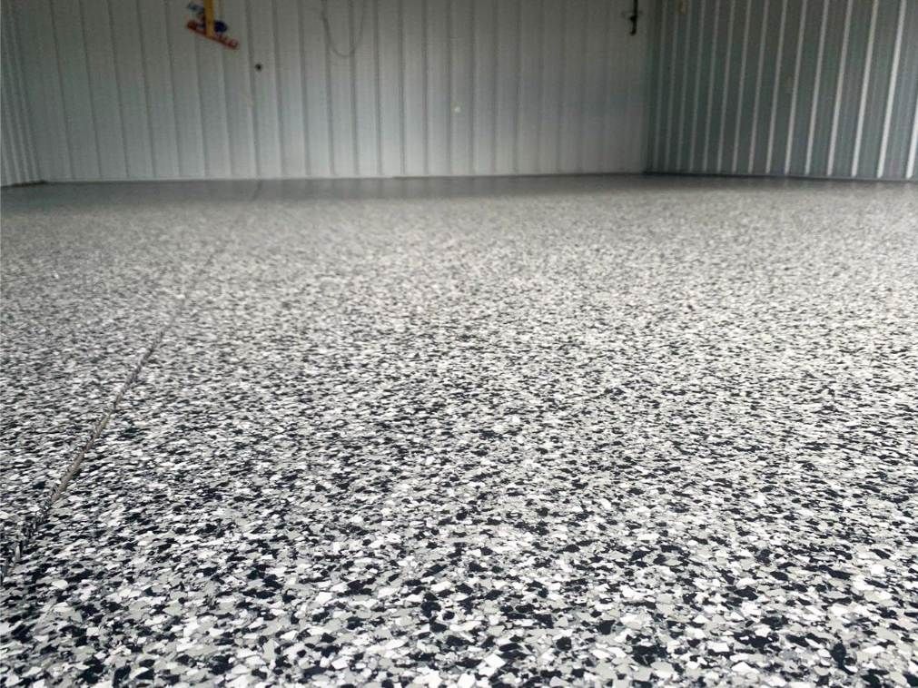 Speckled gray epoxy floor in an empty industrial warehouse with corrugated metal walls