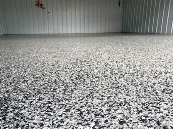 Speckled gray epoxy floor in an empty industrial warehouse with corrugated metal walls