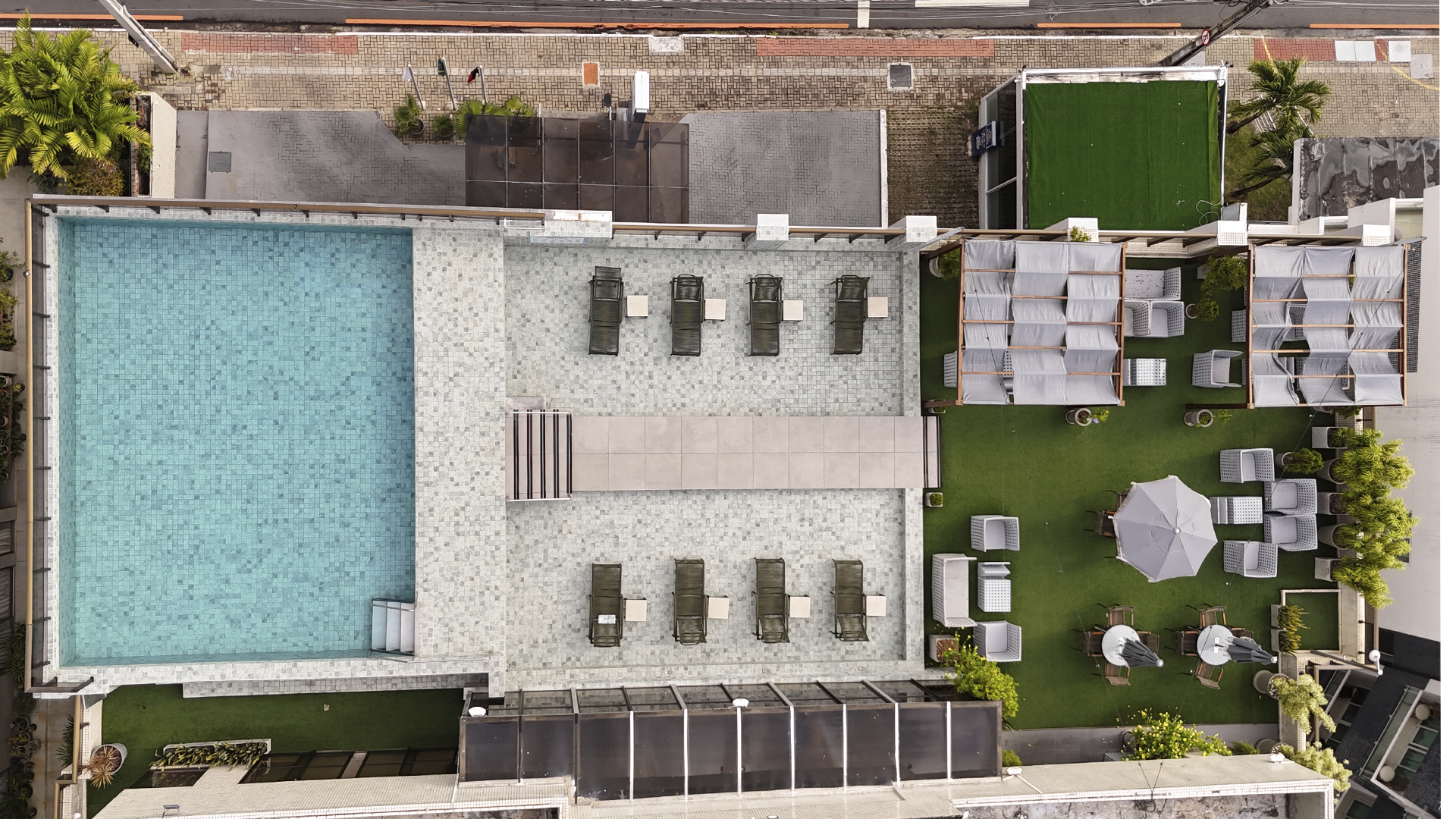 Piscina na cobertura com espreguiçadeiras e vista para o oceano em um dia ensolarado.