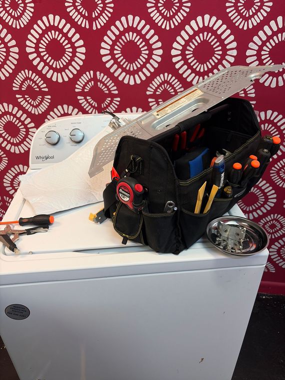 Tool belt on top of a white appliance against a red patterned background