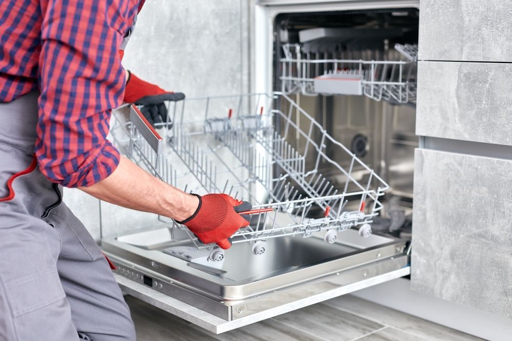 Person loading dishes into an open dishwasher with pull-out racks
