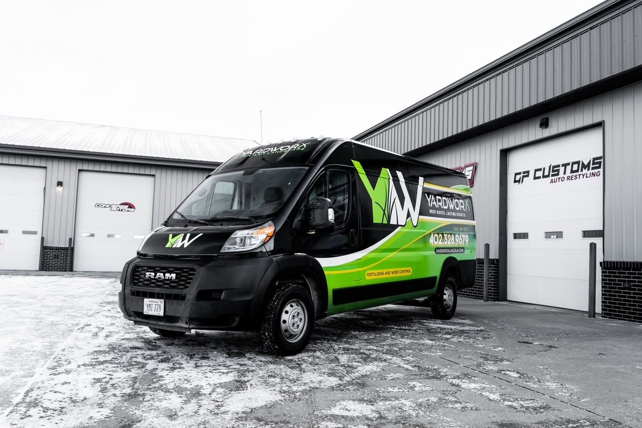 Black-and-green delivery van parked outside a warehouse on snowy ground