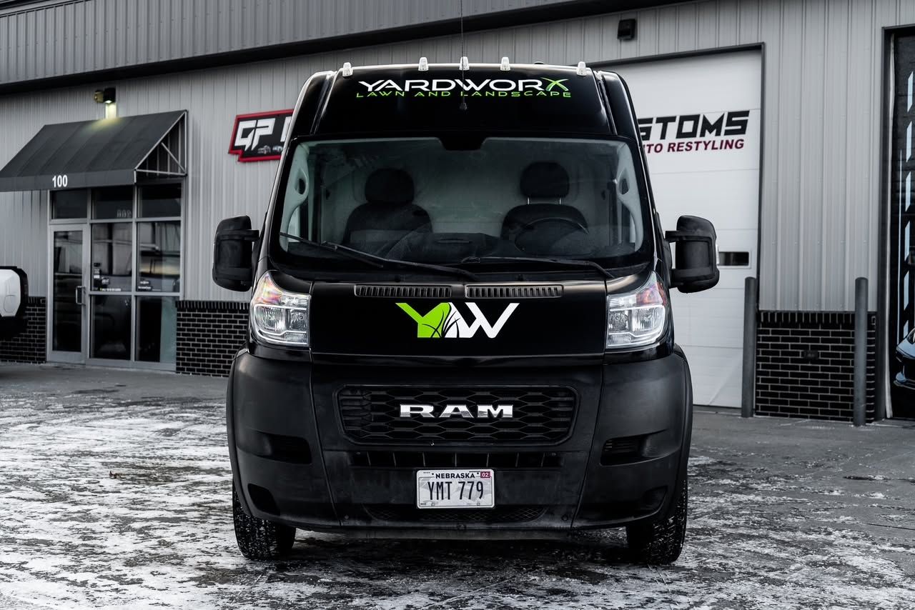 Black RAM van parked outside a custom shop with a green logo on the front.