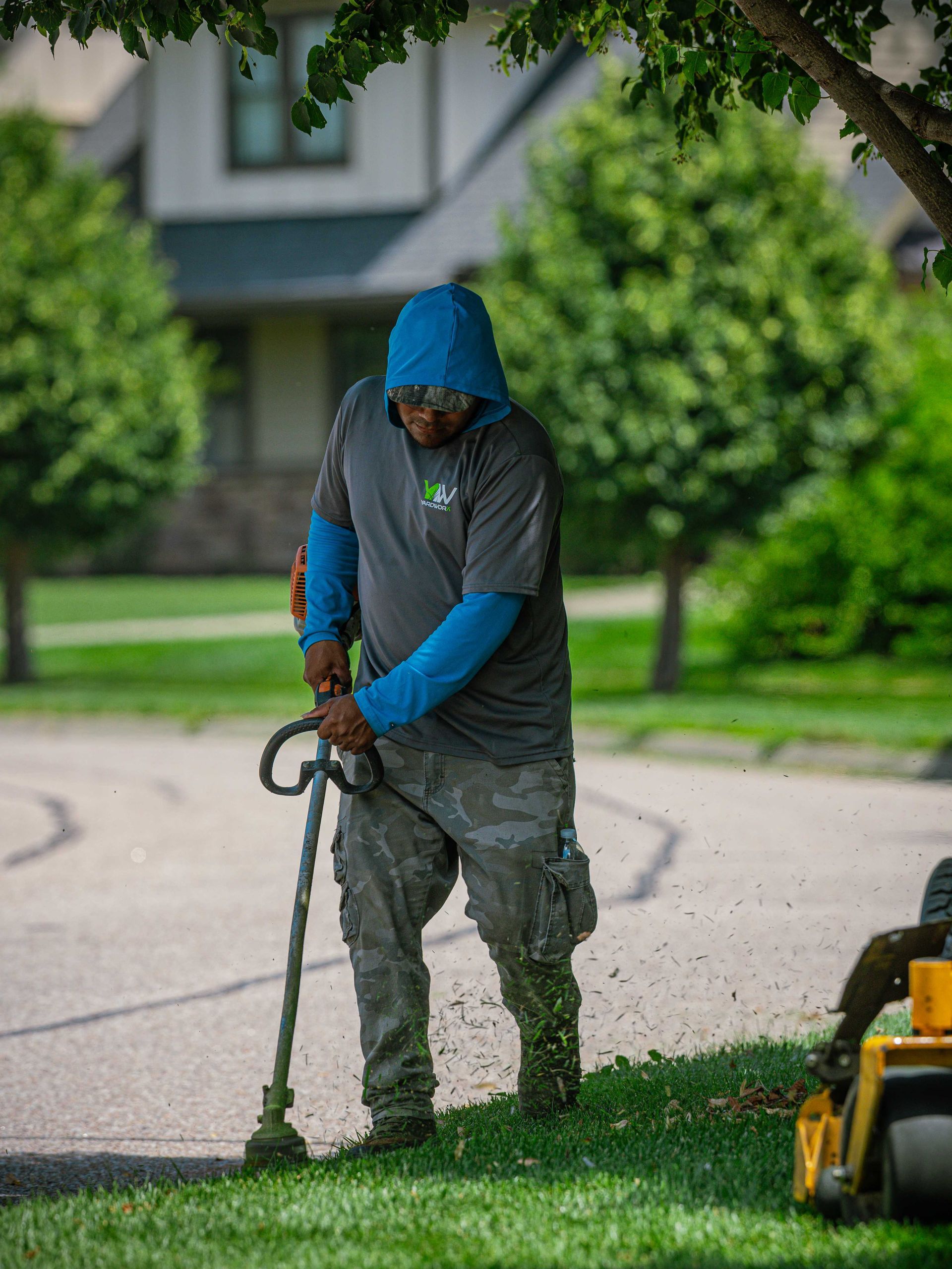 Worker trimming grass with a string trimmer in a residential yard