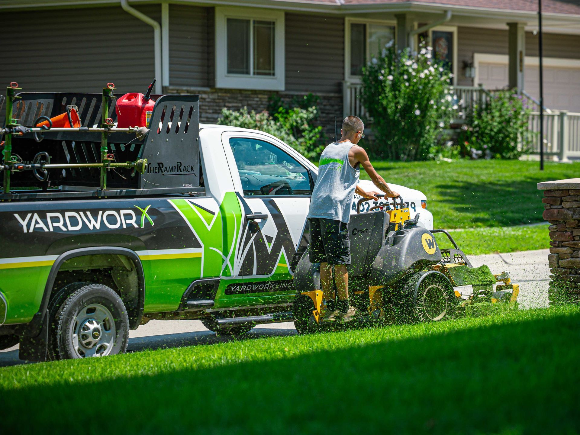 Worker pressure-washing a Yarowney service truck in a suburban yard