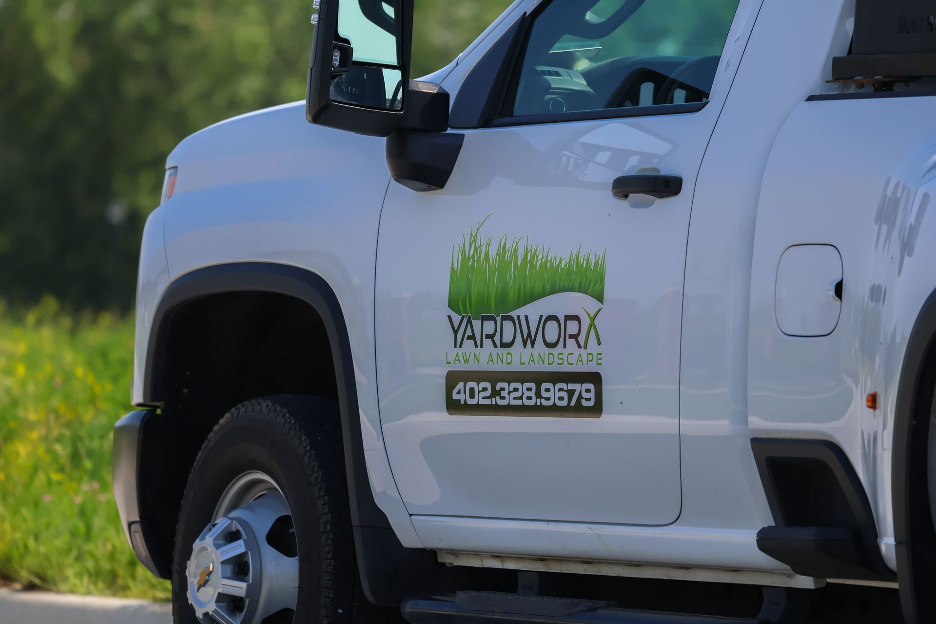White Yardwork truck with logo on the door. Phone number: 402-326-9679.