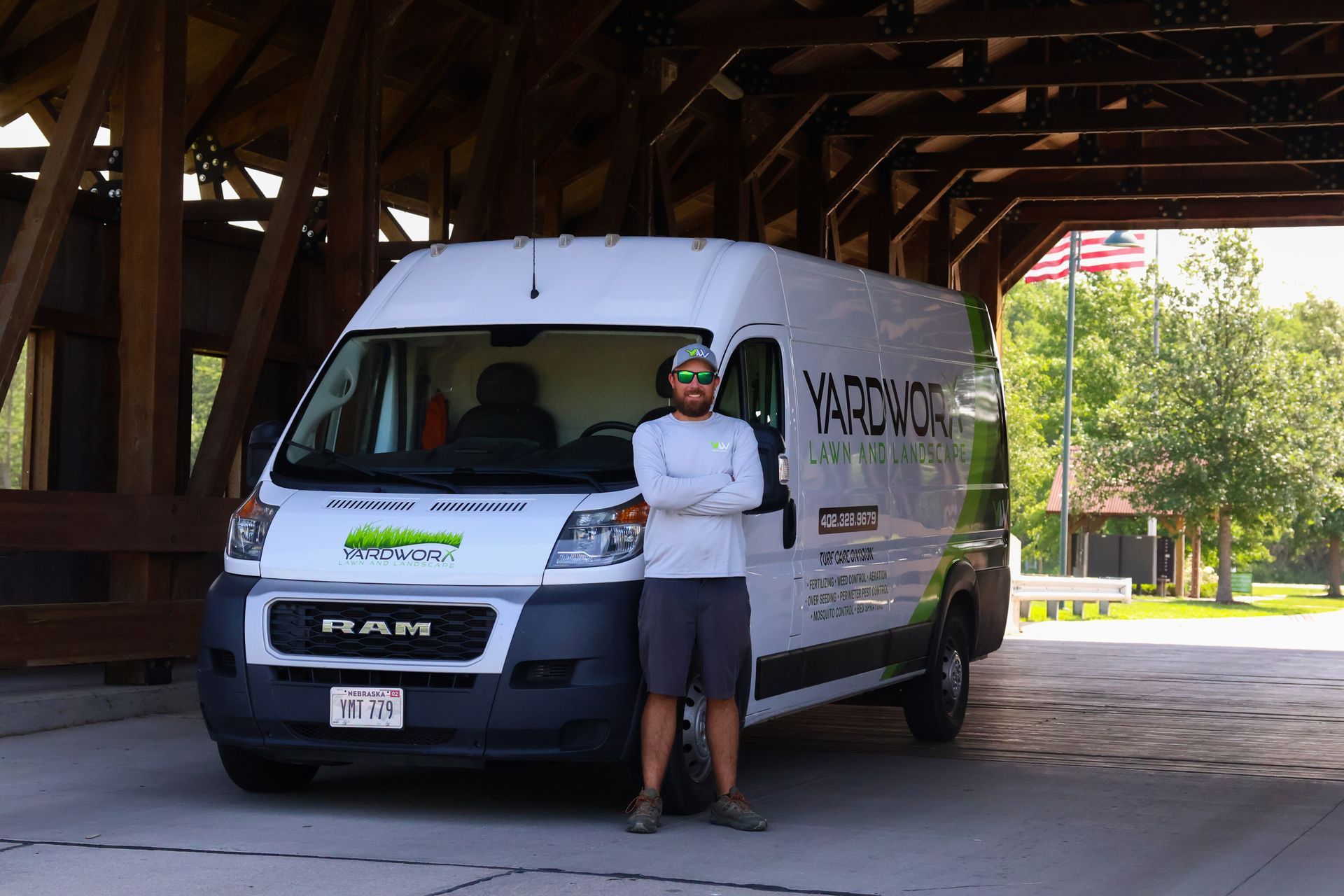 Man standing in front of a white work van under a bridge. Van has 