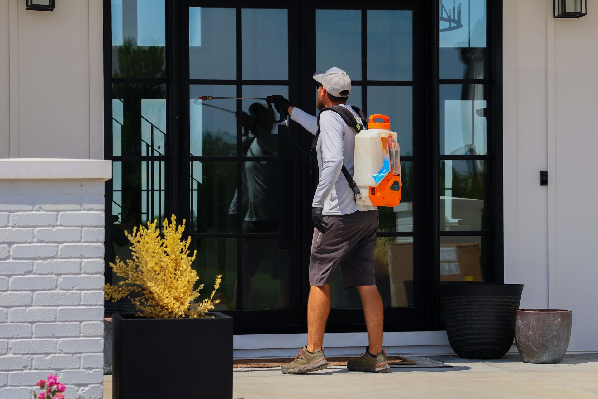 Person spraying front door with backpack sprayer.