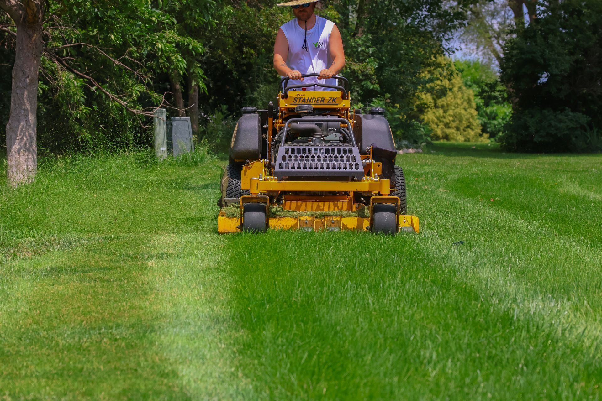 Person mowing grass with a yellow lawnmower on a sunny day.