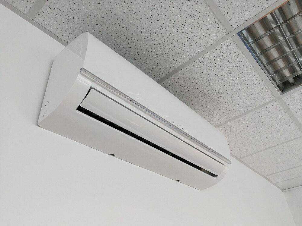 A White Air Conditioner is Mounted to a White Wall — AJM's Air Conditioning Centre in Lismore, NSW