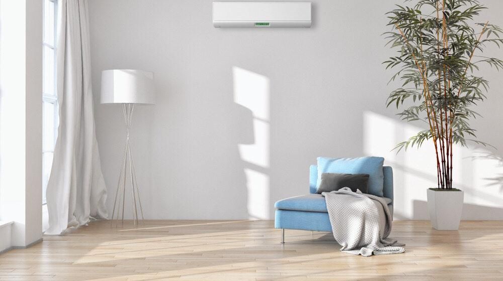 A Living Room With a Blue Chair, a Plant, a Lamp and an Air Conditioner — AJM's Air Conditioning Centre in Goonellabah, NSW