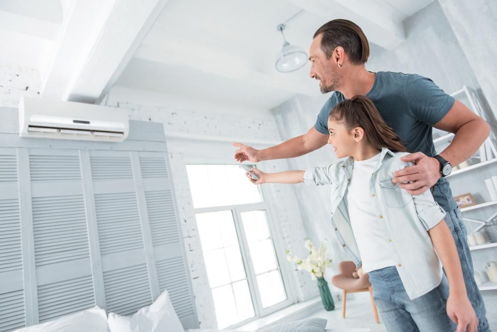 A Man and a Girl Are Adjusting the Air Conditioner in a Living Room — AJM's Air Conditioning Centre in Kyogle, NSW