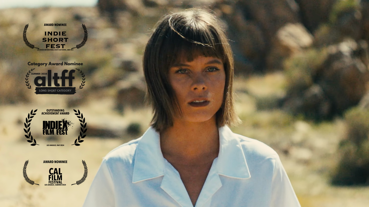 A woman in a white shirt is standing in the desert with awards behind her