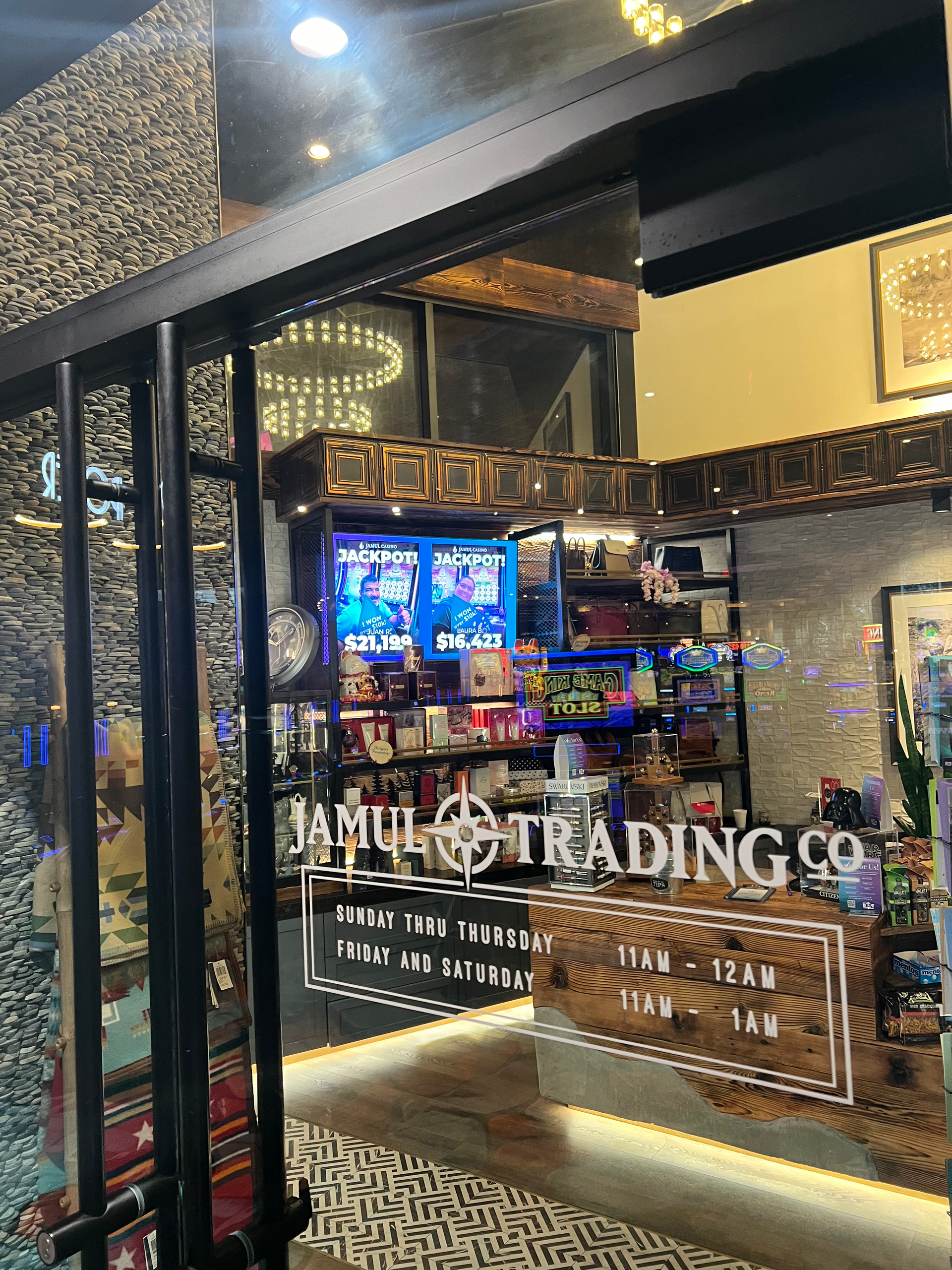 Storefront window for Tumi Trading Co. with illuminated displays and warm interior lighting