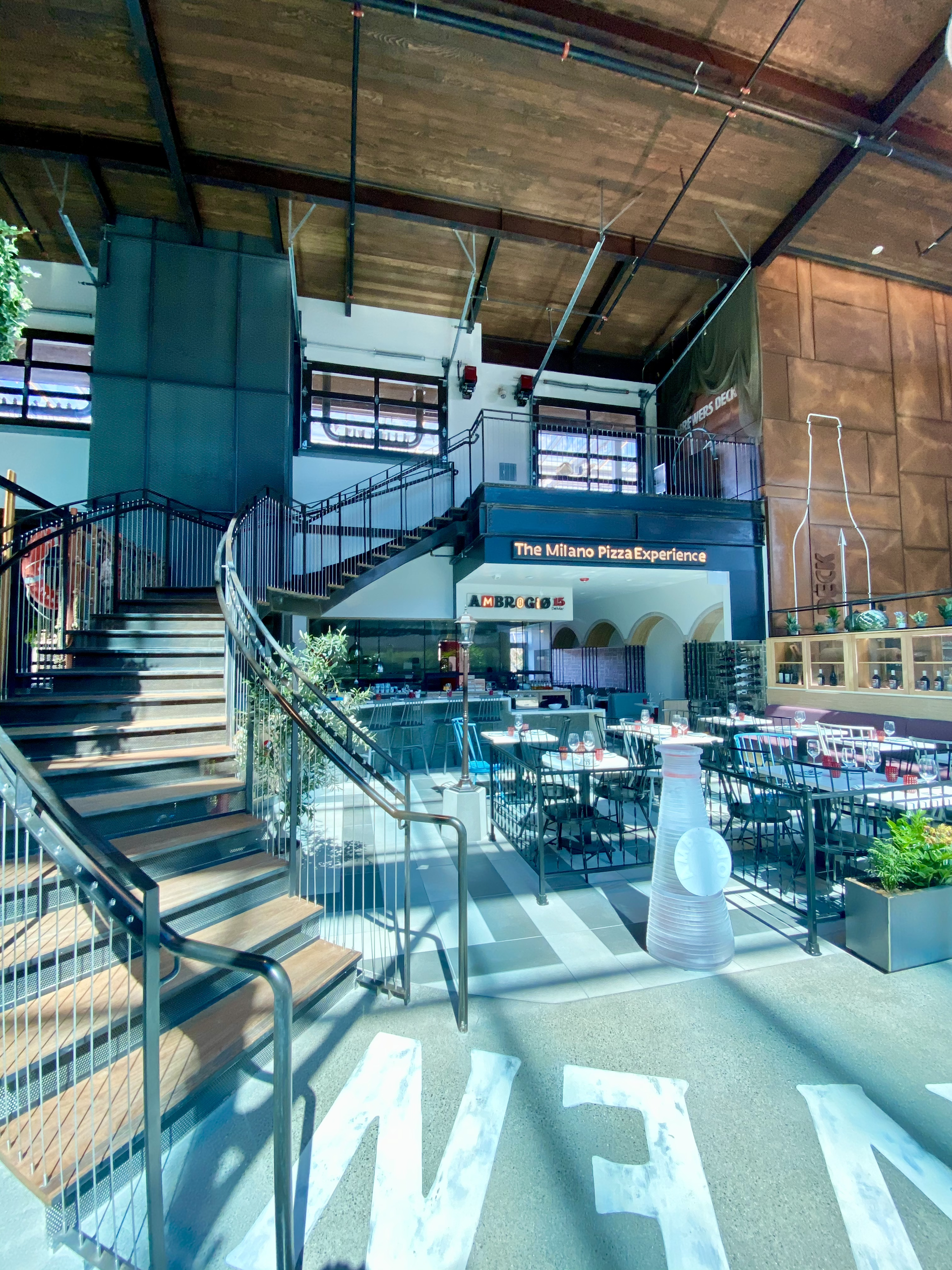 Spiral staircase in a loft-style café or shop with glass display cases and wood ceiling