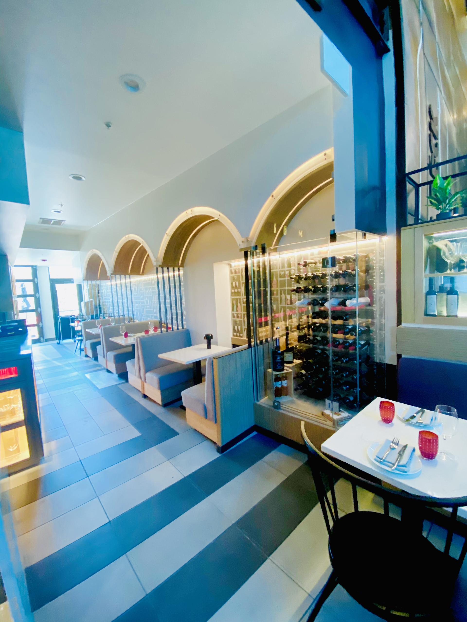 Bright cafe interior with arched booths, blue-and-white tile floor, and a table by the window