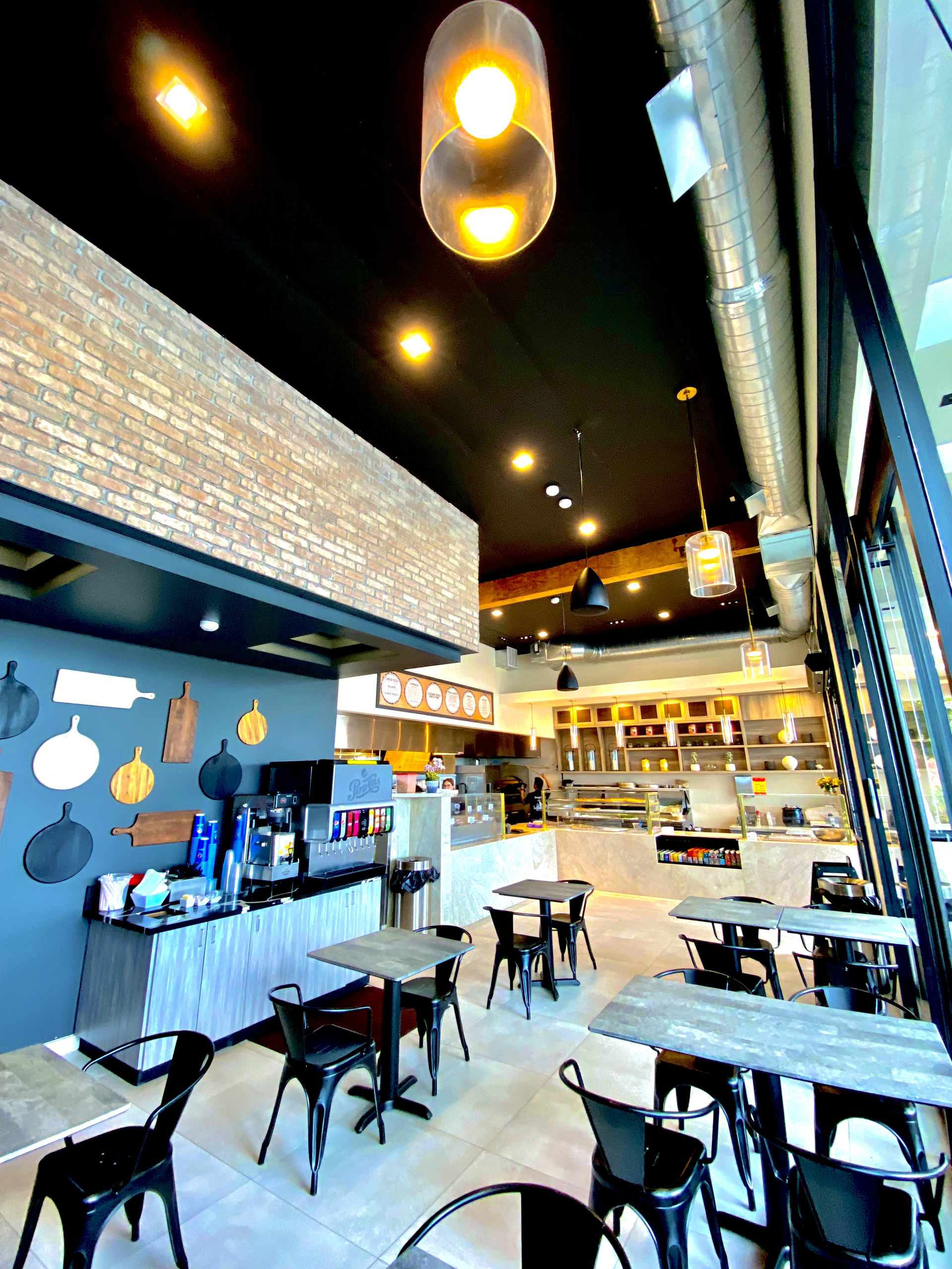 Bright café interior with black tables, blue wall decor, and warm ceiling lights