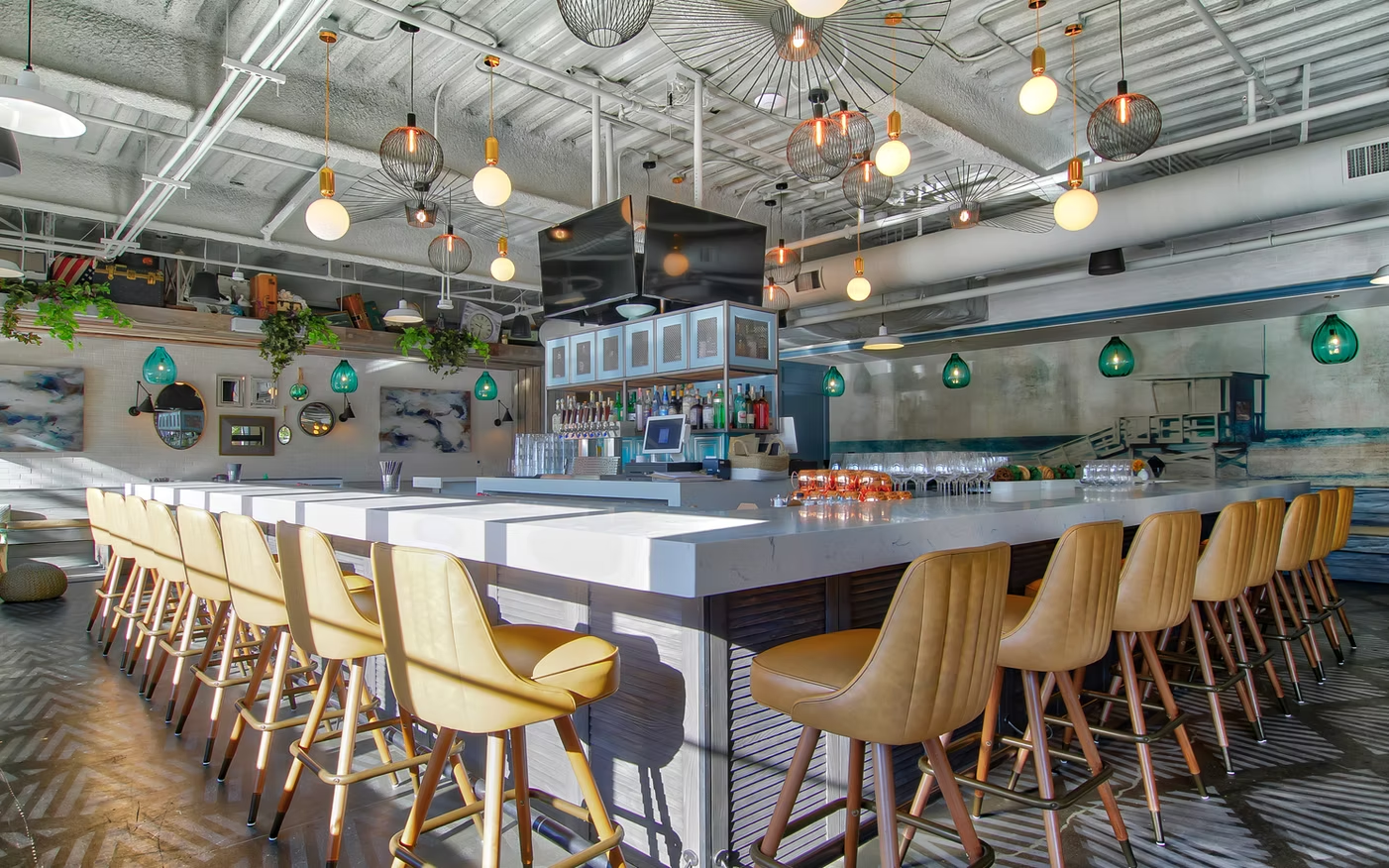Modern bar interior with long counter, wooden stools, hanging lights, and exposed ceiling